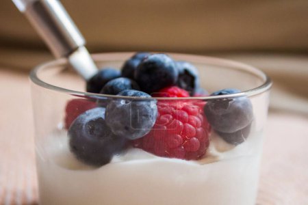 Téléchargez les photos : Un gros plan de tasse en verre de yaourt framboise et mûre sur fond flou - en image libre de droit