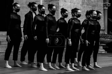 Téléchargez les photos : Un gros plan en niveaux de gris d'un groupe de danseuses debout à l'extérieur avec des masques - en image libre de droit