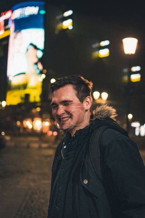 Foto de Un disparo vertical de un hombre rumano sonriente en la calle por la noche - Imagen libre de derechos