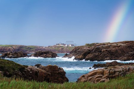 Téléchargez les photos : L'arc-en-ciel se lève des rochers côtiers par une journée ensoleillée à Donegal - en image libre de droit