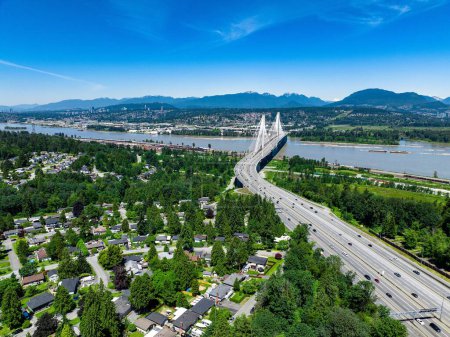 Téléchargez les photos : Un plan de drone du paysage urbain de Coquitlam avec le pont Port Mann et la rivière sous le ciel bleu - en image libre de droit