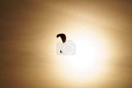 Téléchargez les photos : Une silhouette de parapente volant dans le ciel couchant - en image libre de droit