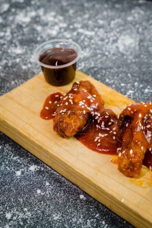 Photo for A vertical shot of Teriyaki chicken with sauce on a wooden board on the kitchen marble table - Royalty Free Image