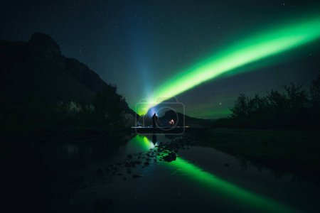 Foto de Las verdes luces boreales sobre el bosque contra una noche estrellada - Imagen libre de derechos