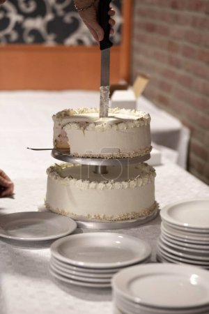 Téléchargez les photos : Un plan vertical du processus de découpage d'un gâteau blanc de vacances à côté des plaques blanches - en image libre de droit