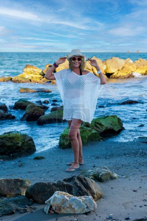 Photo for A vertical of Hispanic female model over 50 years with a white hat and sunglasses on the beach - Royalty Free Image