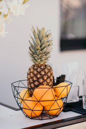 Téléchargez les photos : Un plan vertical d'ananas et d'oranges mis dans un bol sur le fond flou - en image libre de droit