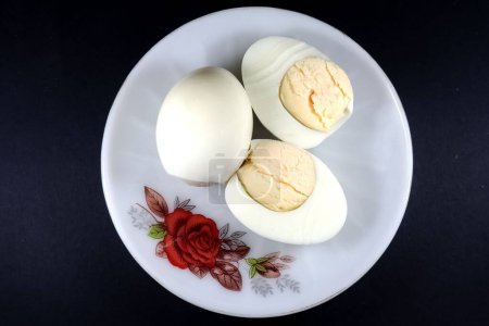 Téléchargez les photos : Une vue de dessus des œufs durs sur une assiette blanche isolée sur un fond noir - en image libre de droit