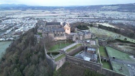 Foto de Una vista aérea de un histórico castillo de Stirling en Stirling, Escocia, en la colina, con un paisaje urbano, y colinas cubiertas de hierba en el fondo - Imagen libre de derechos