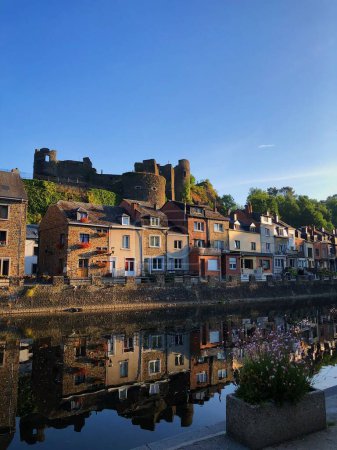 Téléchargez les photos : Un château en ruine et une ligne de bâtiments avec le reflet sur la rivière - en image libre de droit