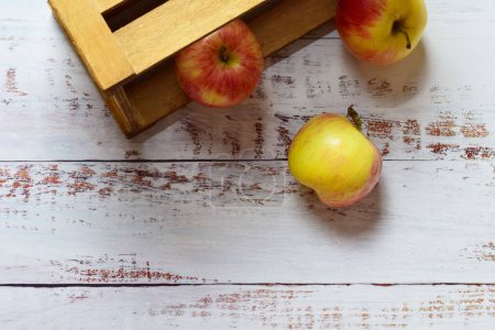 Foto de Una vista superior de manzanas de color rojo amarillento dentro de una caja de madera y se extendió sobre una mesa rústica - Imagen libre de derechos