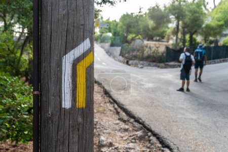 Foto de Un poste de madera con líneas de pintura amarilla y blanca, señalización PR indicativa para excursionistas y caminantes. - Imagen libre de derechos