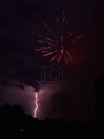 Téléchargez les photos : Un éclair frappe en même temps qu'un feu d'artifice explose dans le ciel - en image libre de droit