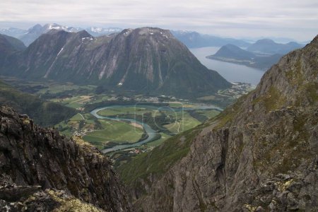 Téléchargez les photos : Un plan en angle élevé de la rivière sinueuse en Rauma Norveentouré de grandes montagnes - en image libre de droit