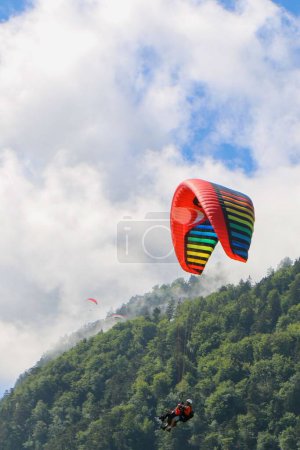 Téléchargez les photos : Un plan vertical du parapente survolant les montagnes vertes fusionné avec des nuages blancs pendant la journée - en image libre de droit
