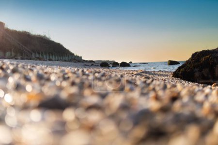 Téléchargez les photos : Lever de soleil panoramique sur la mer depuis la plage de galets - en image libre de droit
