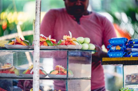 Foto de Un vendedor que corta frutas en un mercado callejero en la India - Imagen libre de derechos