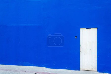Téléchargez les photos : Un énorme mur bleu avec porte métallique blanche - en image libre de droit