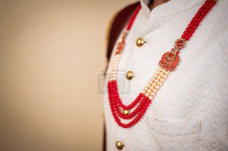 Photo for A closeup of an Indian groom wearing red necklace on a white suit - Royalty Free Image