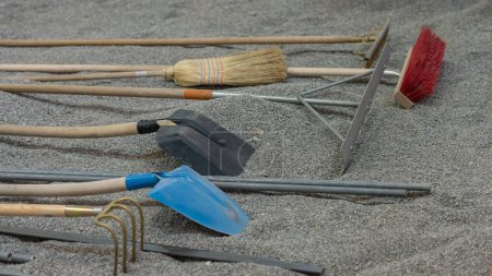 Téléchargez les photos : Un ensemble de balais, pelles et autres outils de jardinage sur granit concassé - en image libre de droit