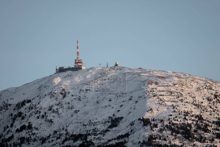 Photo for The view of a snowy mountain peak with a transmitter tower. - Royalty Free Image