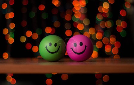 Foto de Un primer plano de bolas sonrientes verdes y rosadas con luces bokeh fondo borroso - Imagen libre de derechos