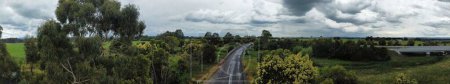 Photo for A panoramic shot of a road surrounded with trees, beautiful nature and sky with clouds - Royalty Free Image