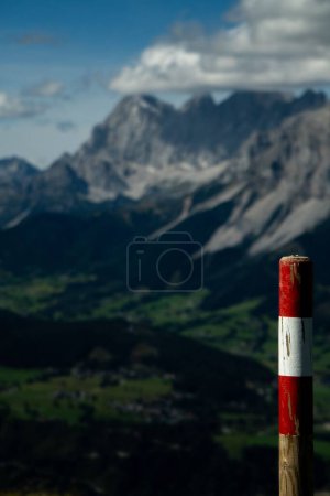 Photo for A vertical closeup shot of a red and white colored border pole on the background of rocky mountains - Royalty Free Image