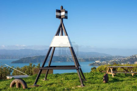 Téléchargez les photos : Une station trigonométrique sur une colline verdoyante donnant sur le port de Wellington sur fond de ciel bleu - en image libre de droit