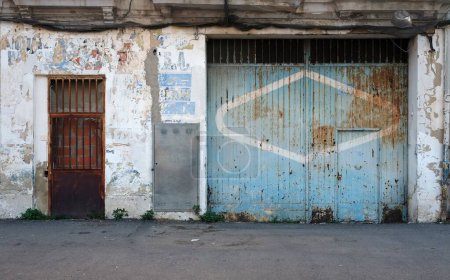 Téléchargez les photos : Façade d'un vieux bâtiment aux murs altérés et aux portes rouillées à Valence, Espagne - en image libre de droit