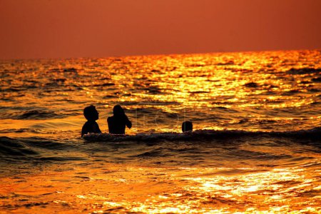 Photo for The silhouette of a group of people in the sea at sunset - Royalty Free Image