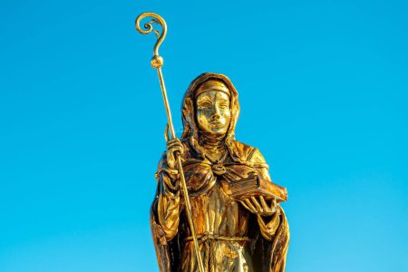 Téléchargez les photos : La statue dorée de Sainte-Walpurga devant un fond bleu - sculpture missionnaire anglo-saxonne - en image libre de droit