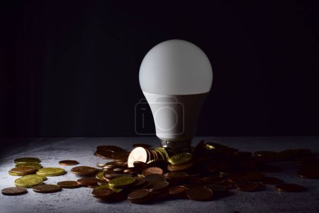 Photo for A light bulb with coins-concept of electricity consumption - Royalty Free Image