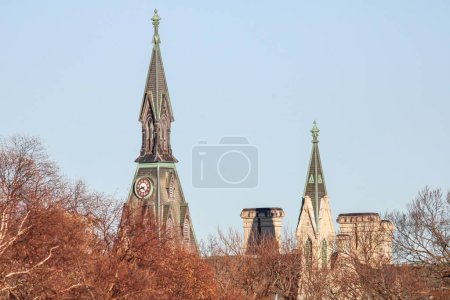Téléchargez les photos : Deux clochers d'église derrière les arbres contre un ciel bleu clair - en image libre de droit
