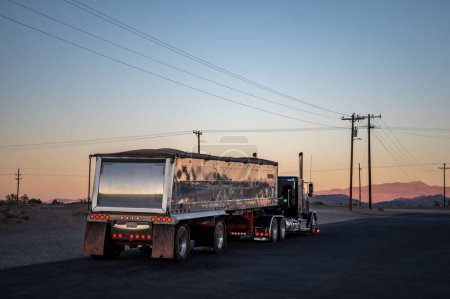 Téléchargez les photos : Camion américain Peterbilt à long nez avec une grande remorque conduisant sur les routes désertes au coucher du soleil - en image libre de droit