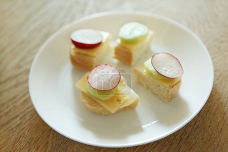 Téléchargez les photos : Un gros plan de mini sandwichs au fromage et radis sur une assiette blanche - en image libre de droit
