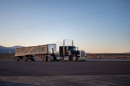 Téléchargez les photos : Camion américain Peterbilt à long nez avec une grande remorque conduisant sur les routes désertes au coucher du soleil - en image libre de droit