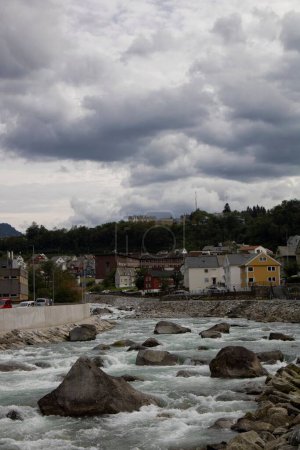 Téléchargez les photos : Plan vertical d'une rivière traversant une ville à côté d'une colline verdoyante - en image libre de droit