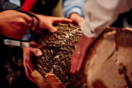 Photo for A selective focus shot of a wooden log being sawed by people in suits, indoors, the concept of tradition and customs - Royalty Free Image