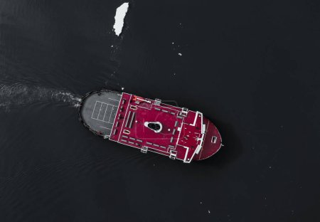Foto de Una vista aérea sobre un barco rojo bajo la luz del sol en un mar - Imagen libre de derechos