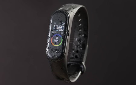 Téléchargez les photos : L'affichage numérique d'un bracelet noir montre intelligente devant un fond sombre - en image libre de droit
