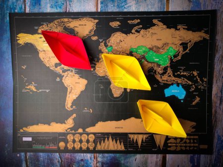 Photo for The colorful paper ships on the world map placed on a wooden table - Royalty Free Image