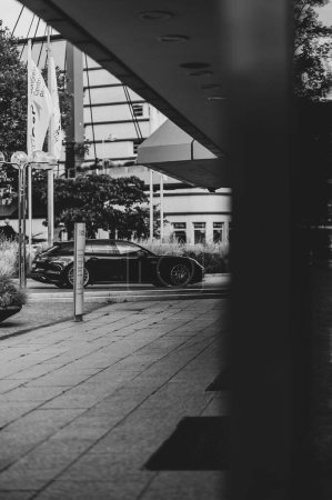 Téléchargez les photos : Une échelle de gris verticale d'une voiture noire garée dans la rue à Pforzheim, Allemagne - en image libre de droit