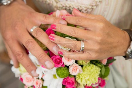 Foto de Un primer plano de las manos del novio y la novia con anillos de boda en un ramo - Imagen libre de derechos