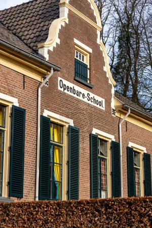 Photo for Exterior brick facade of a small countryside school building with written down sign. TRANSLATION: PUBLIC SCHOOL - Royalty Free Image