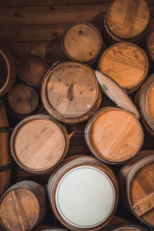 Foto de Un plano vertical de una pila de barriles de vino viejos en el sótano de madera - Imagen libre de derechos