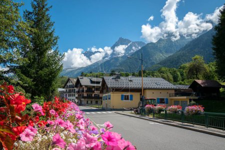 Foto de Una hermosa vista de Tour Du Mont Blanc con casas de colores junto a un jardín con flores rosadas - Imagen libre de derechos
