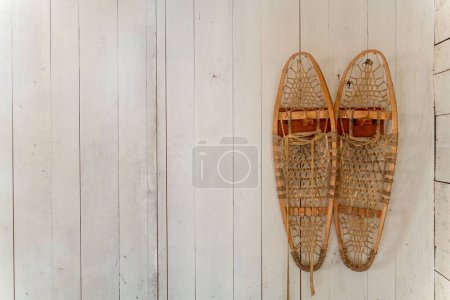 Foto de Un par de zapatos de nieve antiguos sobre un fondo de pared de madera blanca - Imagen libre de derechos