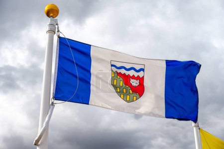 A flag of the Northwest Territories in Canada against a cloudy sky