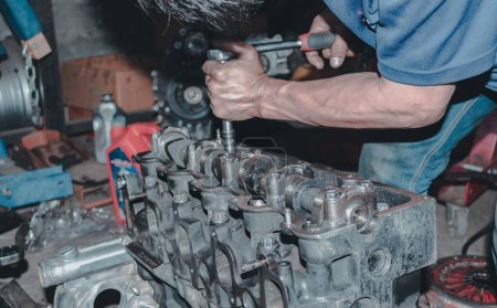 Téléchargez les photos : Le mécanicien automobile réparant le moteur d'une voiture sur le fond flou - en image libre de droit